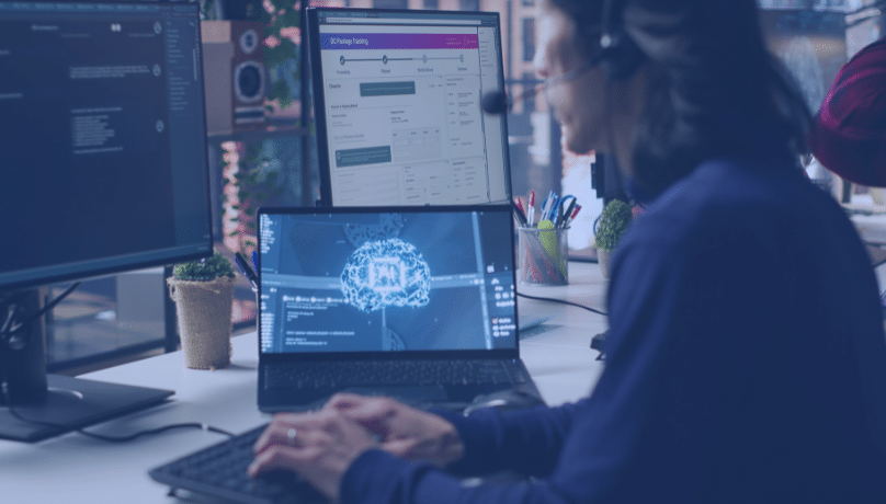 A man at a desk with two monitors and a computer, focused on test automation for rapid product releases.